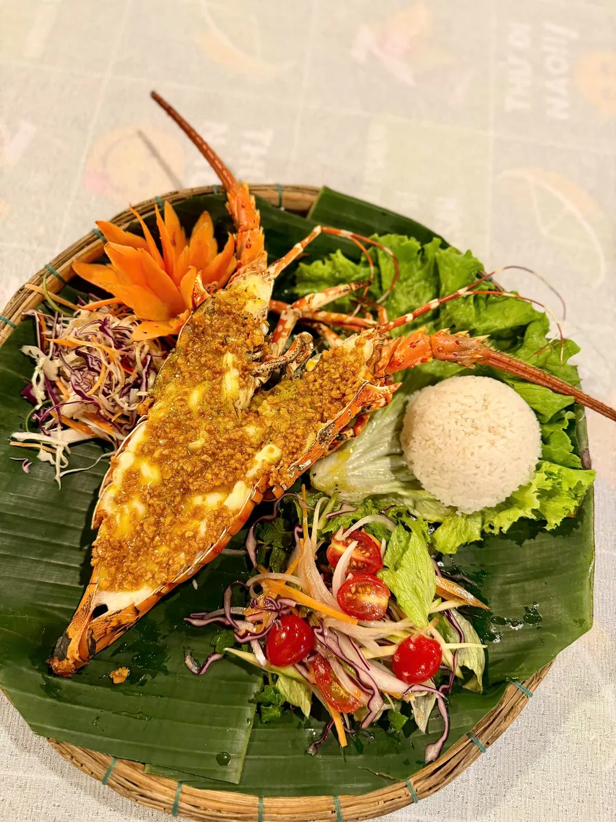 Grilled lobster with garlic butter served on a banana leaf with salad and rice