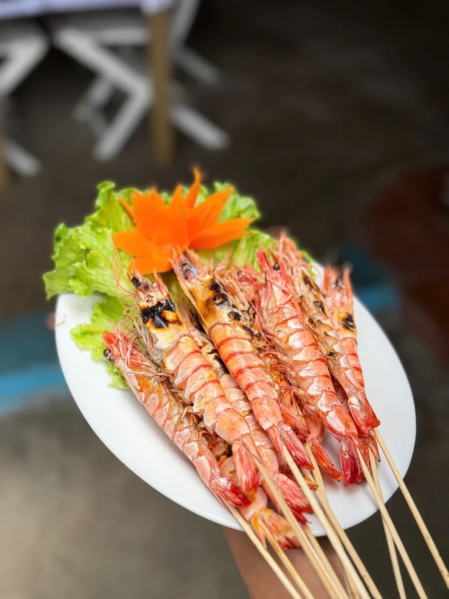Grilled prawn skewers with lettuce and a carved carrot flower
