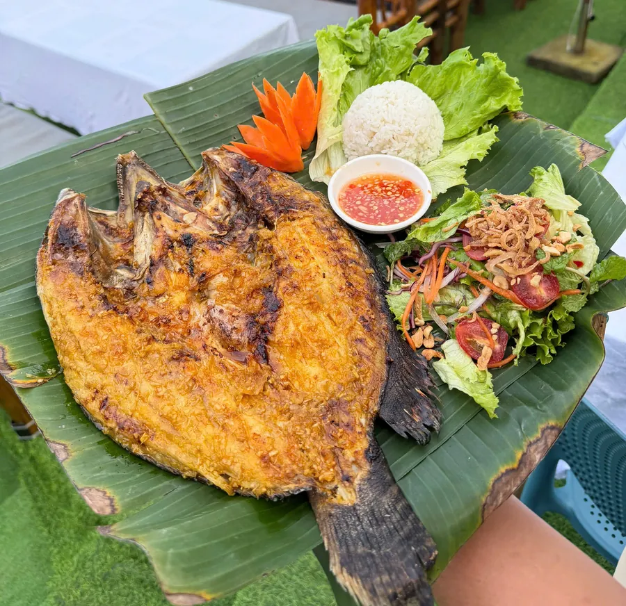 Whole grouper grilled in banana leaf with herb salad, rice and chili dipping sauce